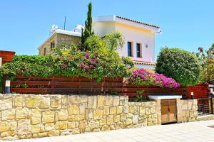een huis met een stenen muur en bloemen bij Villa Olivia Coral in Peyia