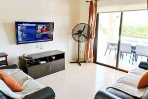 een woonkamer met een flatscreen-tv en een bank bij Villa Olivia Coral in Peyia