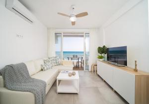 a living room with a white couch and a tv at Luxury Beach home in Fuengirola
