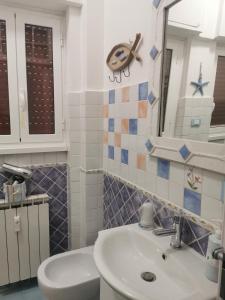 ein Badezimmer mit einem Waschbecken, einem WC und einem Spiegel in der Unterkunft Il Mare di Delfy in Lido di Ostia