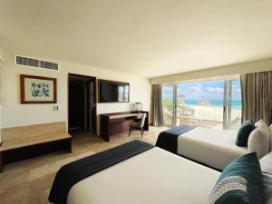 a hotel room with two beds and a desk and a window at The Villas Cancun by Grand Park Royal - All Inclusive in Cancún