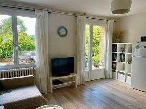 sala de estar con TV y ventana grande en SARLAT Centre ville - Appartement avec jardin et piscine, en Sarlat-la-Canéda