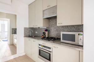 a kitchen with white cabinets and a microwave at Chelsea Posh apartment in London