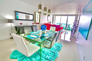 a dining room with a glass table and white chairs at Beautiful penthouse condo with stunning views of both ocean and city in Hollywood