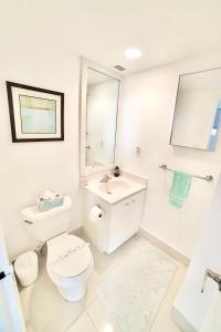 a white bathroom with a toilet and a sink at Beautiful penthouse condo with stunning views of both ocean and city in Hollywood