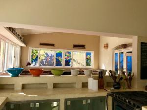 uma cozinha com tigelas num balcão com janelas em Casa Colorida em Pipa
