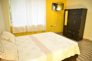 Hotel Tari في Mocoa: غرفة نوم بسرير وخزانة سوداء ونافذة