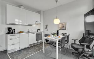 LohalsにあるStunning Apartment In Tranekr With 1 Bedroomsの白いキャビネット、テーブルと椅子付きのキッチンが備わります。