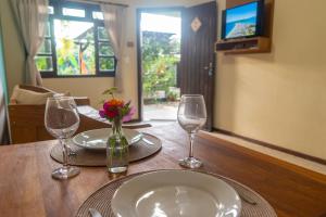 una mesa con dos vasos y un jarrón de flores en Pousada Vila Mariscalia, en Bombinhas