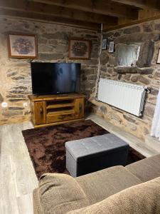 a living room with a tv on a stone wall at Casa Xulián in Monterroso