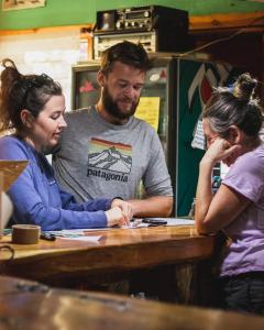 un hombre y dos mujeres sentados en una mesa en Ankatu Hostel en El Bolsón