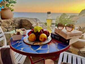 a table with a plate of fruit and glasses on it at Panorama Melina Apartments in Kastrí +27 photos
