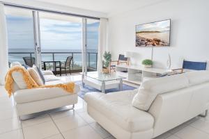 una sala de estar con muebles blancos y vistas al océano. en Grandview Apartments, en Ballina