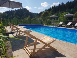 a swimming pool with a chair and an umbrella at Przystanek Letnisko in Komańcza