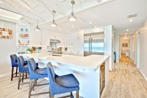uma cozinha com armários brancos e cadeiras azuis em 3BR Beachfront Bungalow em Malibu