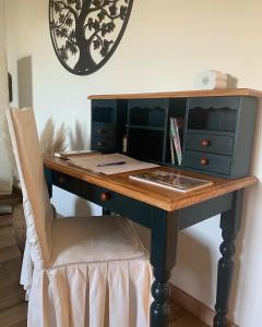 a desk with a chair in a room with a clock at Maison Mard'Or Chambre Forêt in Mardor