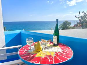 a table with a bottle of wine and two glasses at Panorama Melina Apartments in Kastrí