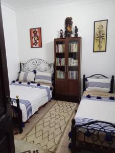 een slaapkamer met 2 bedden en een boekenplank bij Dar 36 LAKSIBA in Marrakesh
