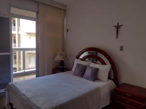 a bedroom with a bed with a cross on the wall at Apartamento Praia do Forte Familiar com piscina in CFB