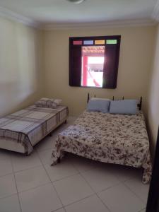 ein Schlafzimmer mit zwei Betten und einem Fenster in der Unterkunft Casa veraneio em Canto de Arembepe in Camaçari