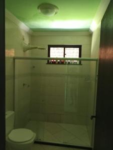 ein Badezimmer mit Dusche, Toilette und Fenster in der Unterkunft Casa veraneio em Canto de Arembepe in Camaçari
