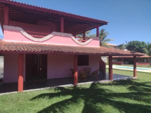 ein Haus mit einem roten Dach und einem grünen Hof in der Unterkunft Casa veraneio em Canto de Arembepe in Camaçari