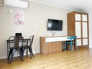 a room with a desk with a tv and chairs at Pupuke Manor Motel in Auckland