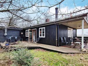 ein kleines schwarzes Haus mit einer Veranda und einer Terrasse in der Unterkunft Holiday home Aars II in Års
