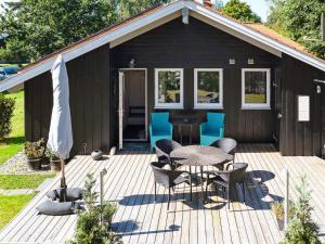 a black shed with a table and chairs on a deck at 8 person holiday home in Gilleleje in Gilleleje