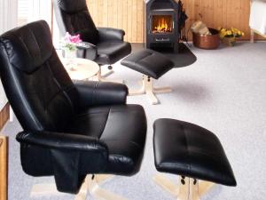a room with three black chairs and a fireplace at 4 person holiday home in Hvide Sande in Bjerregård