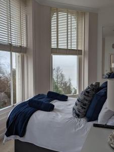 a bedroom with a large bed with two windows at 1 Bed Apartment - Sea view in Shanklin