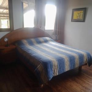 1 dormitorio con 1 cama con manta azul y blanca en Cabaña en la playa. ventanales y terraza al mar, en Salinas