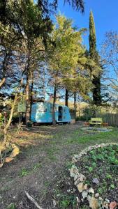 einem blauen Wohnwagen, der auf einem Feld neben Bäumen parkt in der Unterkunft Ir por ai Arrábida in Azeitão