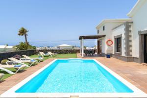 een zwembad in een tuin met stoelen en een huis bij Villa Esterlicia in Playa Blanca