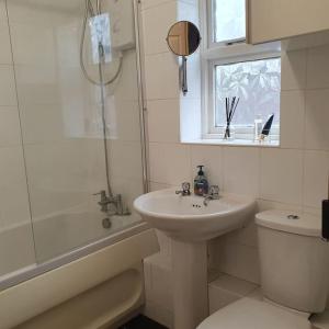 a white bathroom with a sink and a toilet at Ideally located contemporary 3 bed spacious house in Wainscot