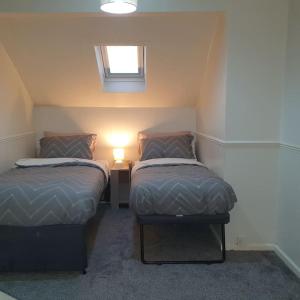 een kleine kamer met 2 bedden en een lamp bij Ideally located contemporary 3 bed spacious house in Wainscot