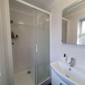 a white bathroom with a shower and a sink at Ideally located contemporary 3 bed spacious house in Wainscot