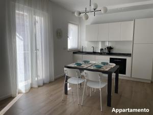 cocina con mesa negra y armarios blancos en Casa di Cìì, en Porto San Giorgio