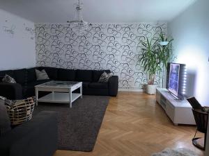 a living room with a black couch and a tv at Säfsen Stay in Ludvika