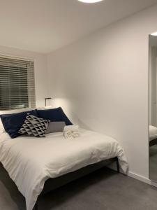 a white bedroom with a large bed with blue pillows at New Modern apartment in the heart of city center Delft in Delft