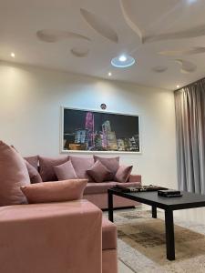 sala de estar con sofá rosa y mesa en Al-Aniqa Furnished Apartments en Riad