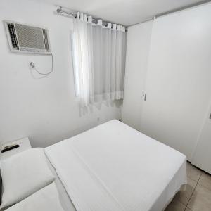 a white room with a bed and a window at Atlantis Residence in Vitória