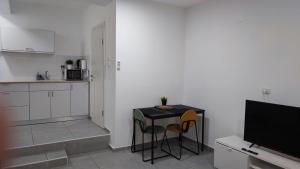 eine Küche mit einem Tisch, 2 Stühlen und einem TV in der Unterkunft Studio Apartment 12 Minutes from Bahai's garden in Haifa