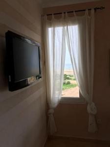 Cette chambre dispose d'une télévision et d'une fenêtre avec des rideaux blancs. dans l'établissement A7 Maison Blanche Imi ouaddar, à Agadir
