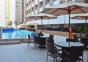 a patio with tables and chairs with umbrellas and a pool at GoldFlat in João Pessoa