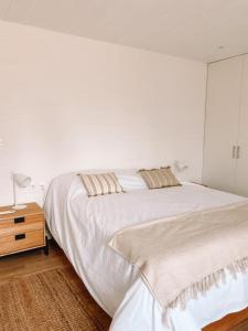 a white bedroom with a large bed and a nightstand at Casa de mar - José Ignacio in José Ignacio