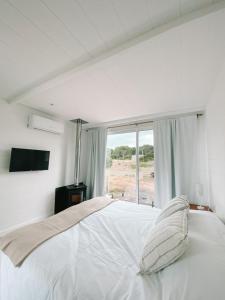 a white bedroom with a large bed with a window at Casa de mar - José Ignacio in José Ignacio