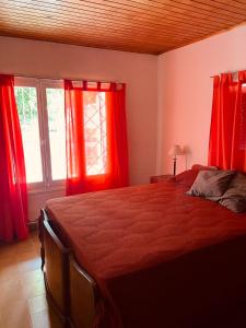 1 dormitorio con cortinas rojas y 1 cama grande en Casa Tito en Tunuyán