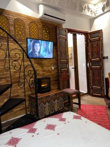 1 dormitorio con 1 cama y TV en la pared en Dar Dahab, en Fez
