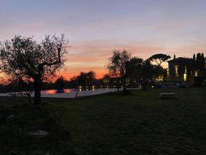 um pôr-do-sol sobre um parque com um edifício e árvores em Villa Paladini em Montefiascone